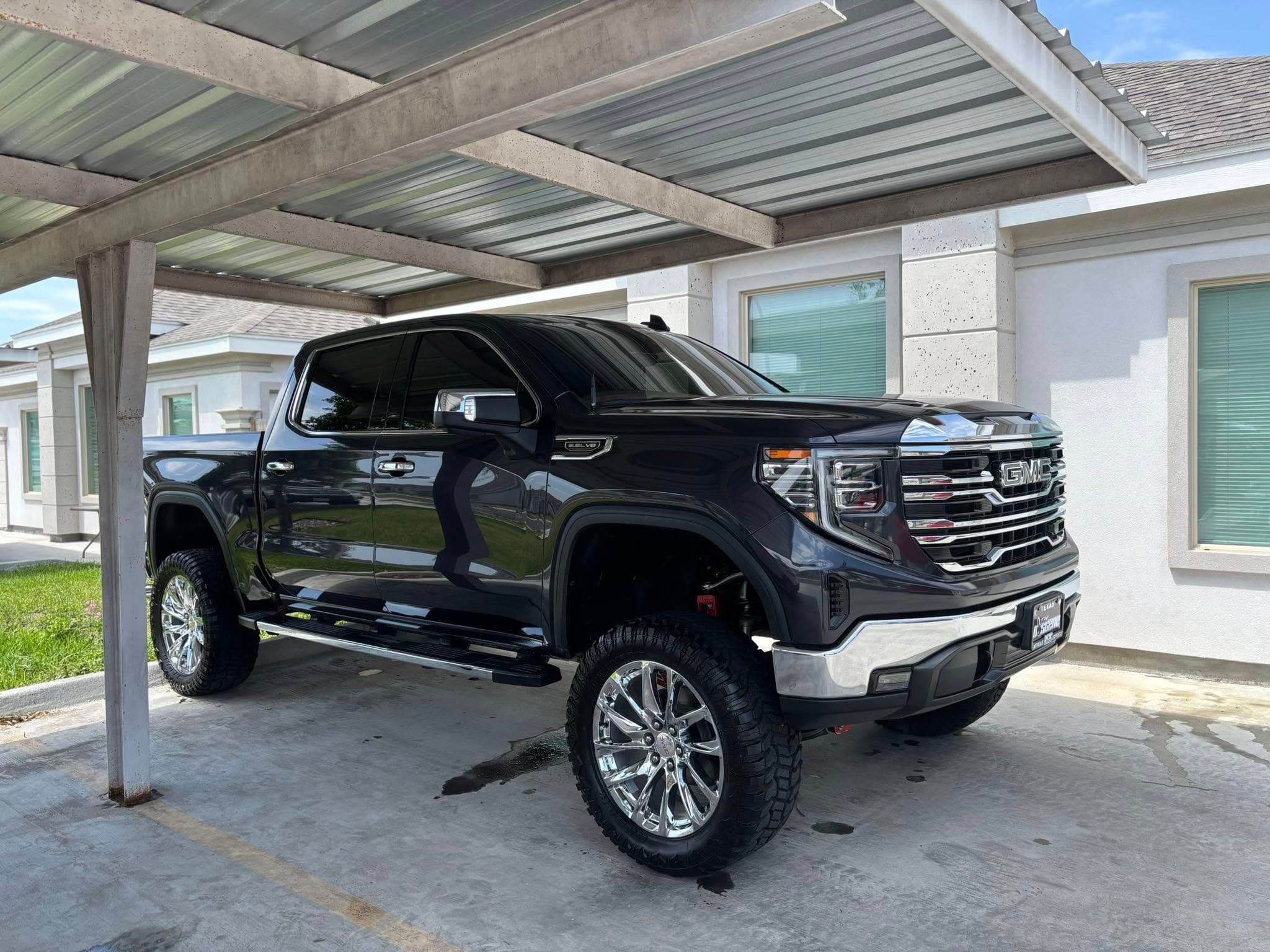 Black GMC Sierra with chrome accents under a carport, showroom finish after detailing